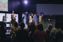 Audience with arms raised at a worship concert.