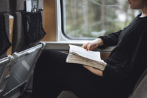Girl reading her bible on en empty train.