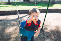 a toddler boy on a swing set 