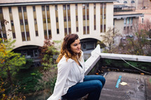 young woman sitting on the edge of a roof 
