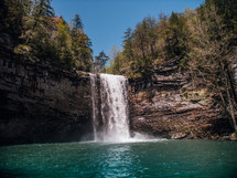 waterfall over the side of a cliff into a swimming hole 