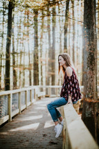 teen girl sitting on a wood railing 