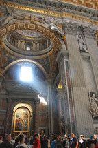 Light streams through the window onto the tourists inside St. Peter's Basilica in Vatican City