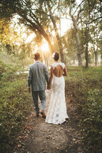 bride and groom walking along an outdoor path holding hands