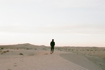 a man walking on sand dunes 