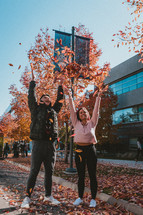 couple tossing up fall leaves 