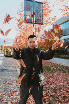 man tossing fall leaves 