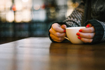 a woman with painted nails holding a coffee mug