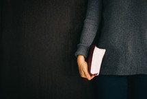 a woman holding a Bible at her side