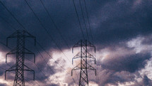 power lines under gray clouds in a sky at sunset 