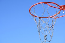 a metal chain basketball net against a blue sky 