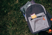 pencils in a book bag on the grass