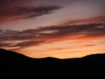 sunset behind a silhouette of hills