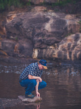 a man standing on a rock near a stream 