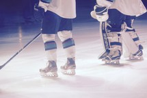 hockey players standing in the spotlight on the ice 