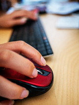 a woman's hand on a computer mouse and keyboard at a desk