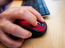 a woman's hand on a computer mouse on a desk