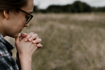 a woman praying in a field 