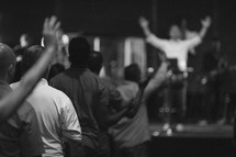 parishioners with raised hands at a worship service 