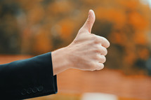 Winner. Success. Hand of man in business clothing gives thumbs up. Guy showing gesture of approval