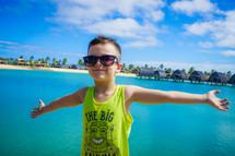 a boy with open arms standing in front of tropical vacation property 