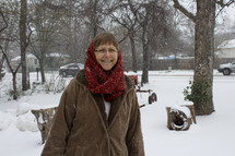 a woman in a scarf standing outdoors in the snow 