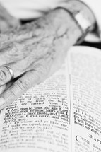 Elderly hand on page of Bible open to Isaiah 46:4.