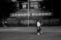 Young Chinese women walking along a road near a sign.