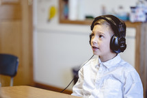 a boy sitting in a classroom wearing headphones 