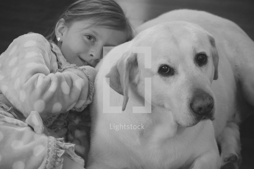 A little girl snuggling with her labrador retriever 