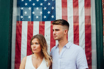 a couple standing in front of an American flag 