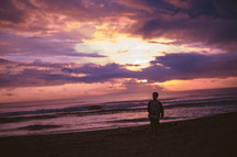 silhouette of a man standing on a beach at sunset 
