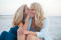sisters talking and laughing on a beach 