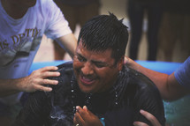 A man is lifted from a baptismal pool.