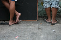 feet in sandals on a sidewalk 
