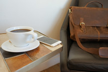 computer bag in a chair, coffee cup, and cellphone 