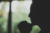 silhouette of a young woman in prayer 