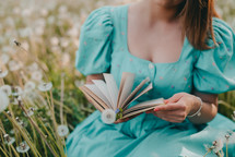 Hands of woman turns over pages of old paper book. Lady in retro or vintage dress reading interesting novel while sitting on nature. Atmospheric scene. Education, science, university concept. photo
