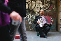 An older man plays the accordion on the street