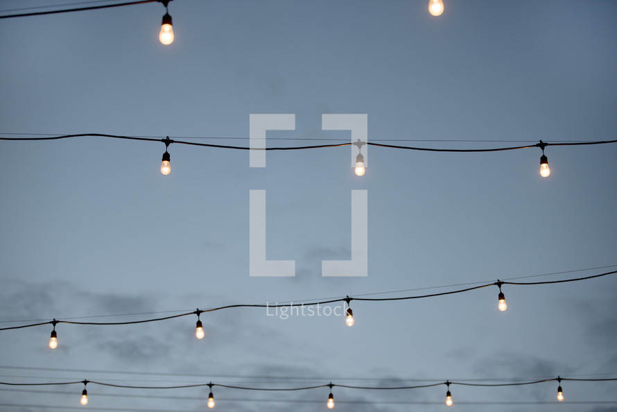 hanging lightbulbs over a courtyard 