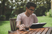 a young man reading a Bible in his backyard 