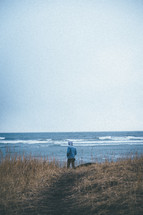 a man standing on a shore looking out at the water 
