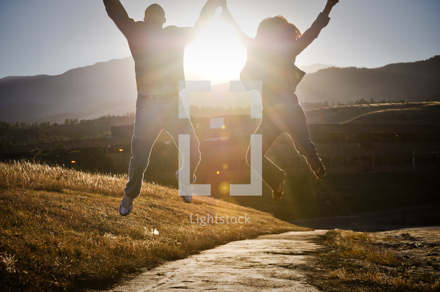 a couple celebrating holding hands and jumping into the air 