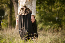 Woman standing outside in a field of tall grass.
