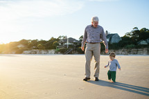 grandfather and grandson walking on a beach 