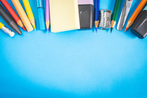 Different kind of school/office supplies for studying, on a blue background. Back to school.