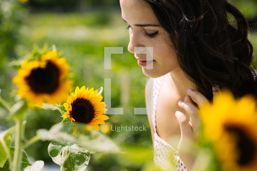 A young woman standing among sunflowers.