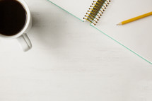 a pencil and notepad with coffee 