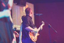 man playing a guitar at a worship service 