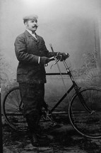 a vintage photograph of a man with a bicycle black white 